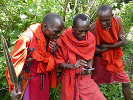 Daniel Meipuki, Patrick Koyati and David Ntiyani in the Loita Forest, learning to use the Mara EleApp by Joyce and Petter. In the enlarged photo they are very happy when first real record (sign of elephant) is saved successfully. (©ElephantVoices)